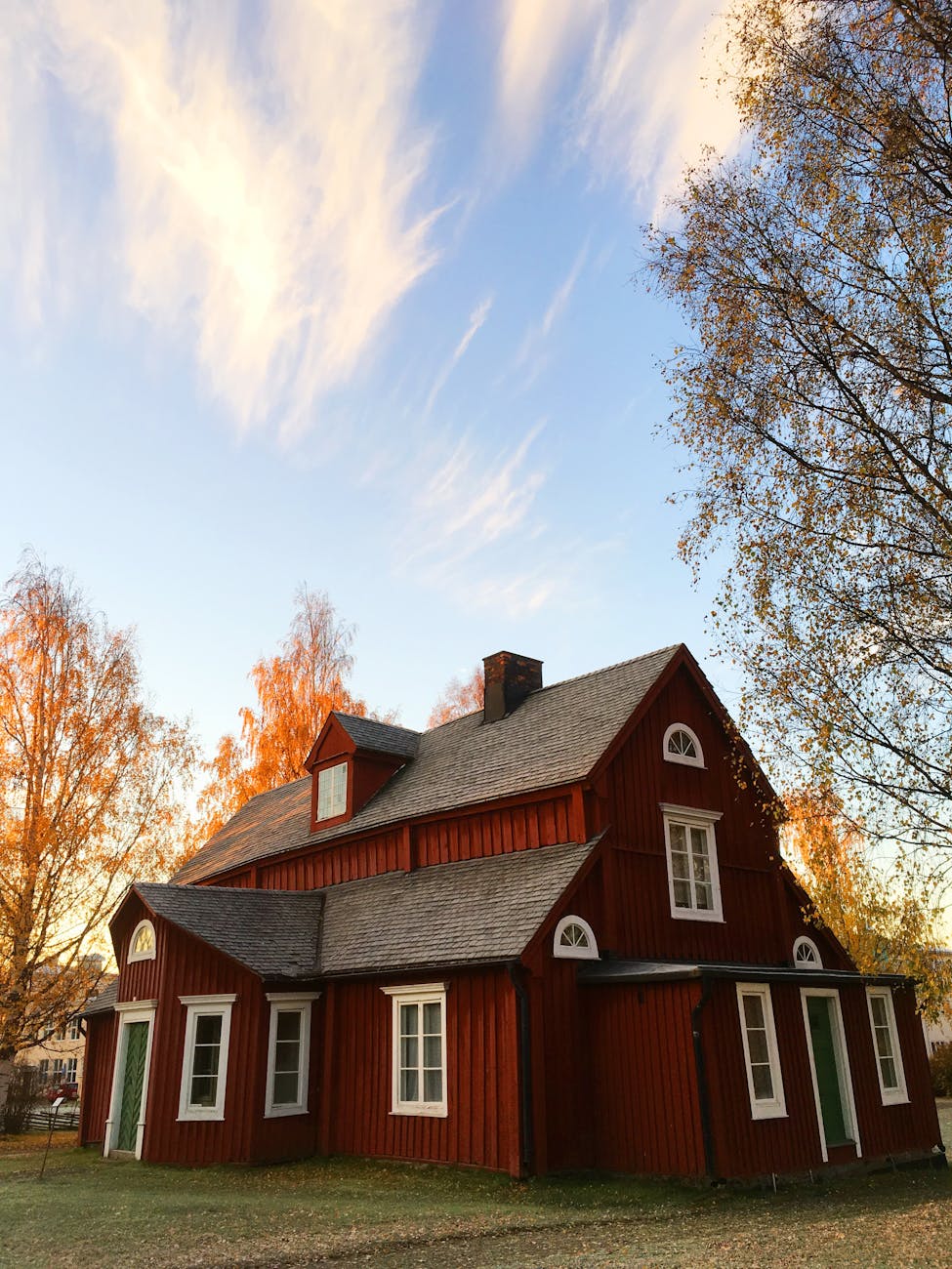 A brick house with a paved driveway and a trimmed front lawn.